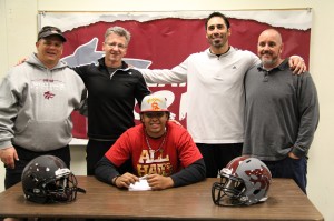 CHS football coaches (from left to right) Terrance Lynch, Mike Collins, Ryan Campuzano, and Shane Hile stand behind graduated senior Jordan Austin (center). Austin signed to USC on Dec. 19 in the health room at CHS and has already started his football career at USC.