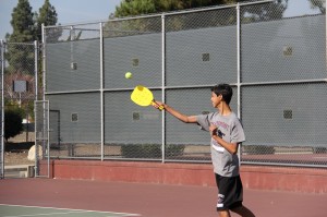 Freshman Jesse De La O swings his racquet in an attempt to hit the wiffleball in a pickleball match.